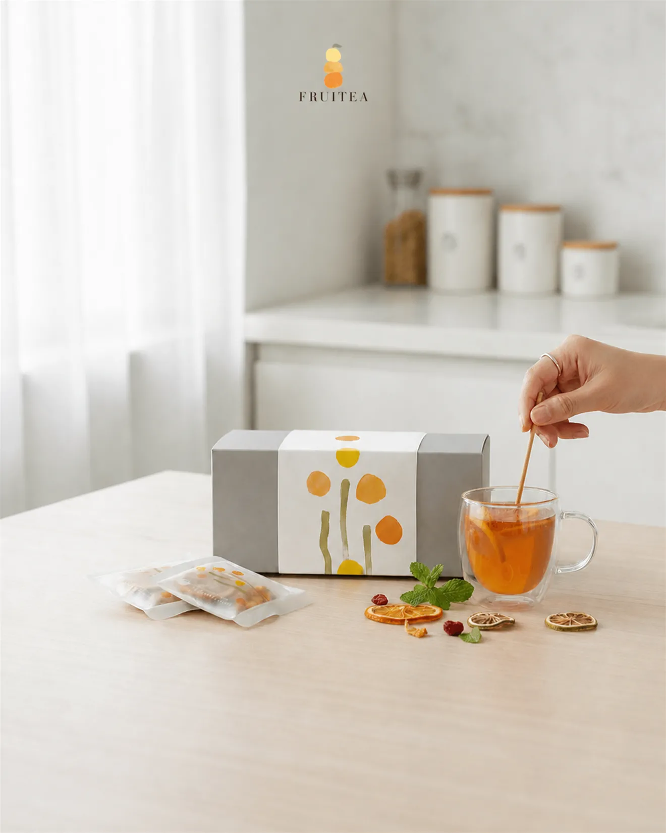 明亮廚房餐桌上的 FRUITEA 馥緹果禮盒、兩包獨立果乾水與透明杯，手正攪拌橙色果乾水