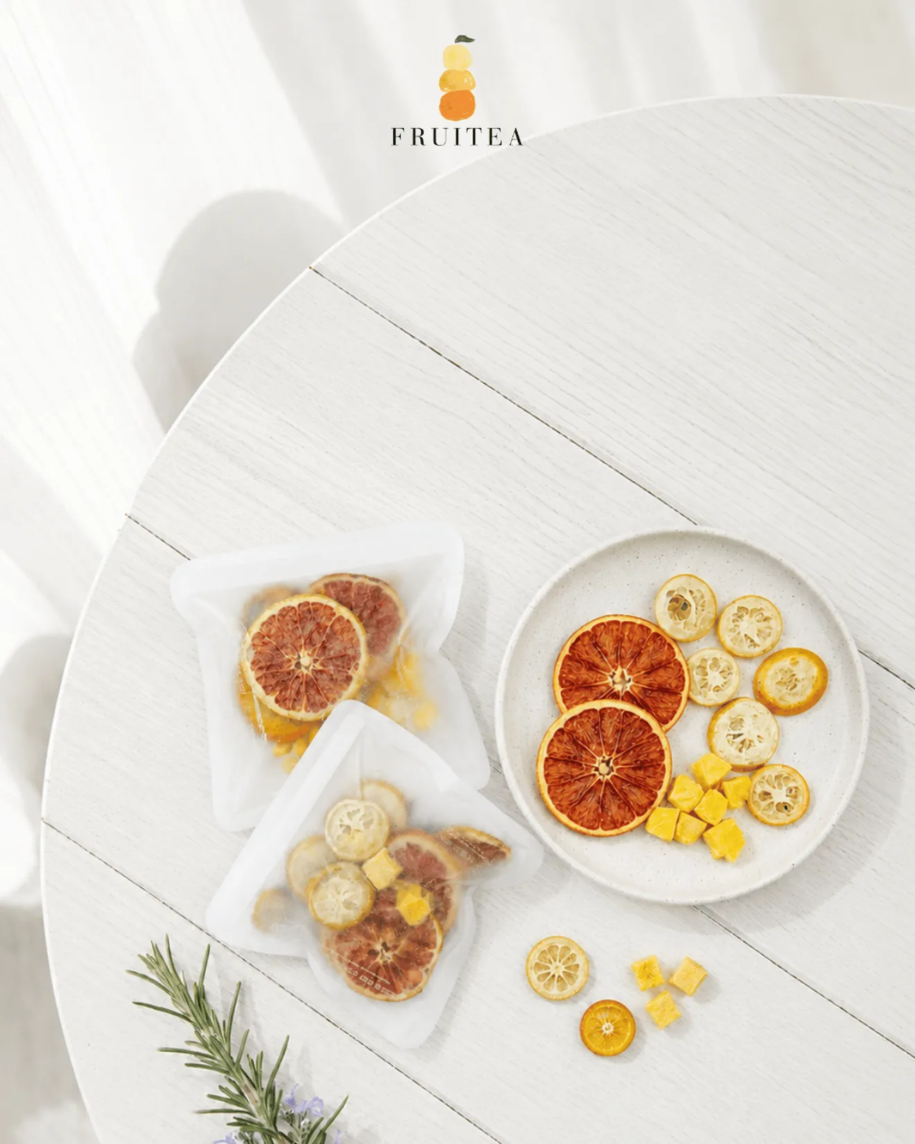 白色日光桌面上的 FRUITEA 馥緹果果乾水獨立包與盤裝柑橘果片,呈現包內可見的真實水果